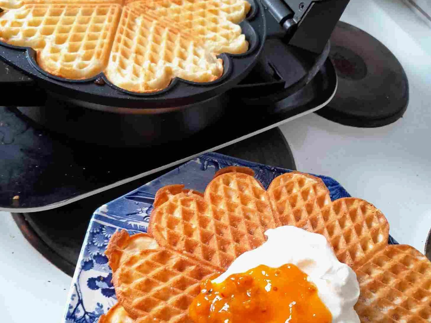 Nygräddade våfflor på blått fat med orange havtornssylt och vispad grädde